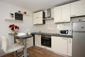 萨格勒布Apartments Zagreb Schone的厨房配有白色橱柜和带微波炉的桌子。