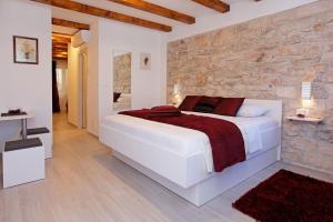 尼亚卢卡Luxory D-Rooms的卧室配有一张白色的大床和石墙