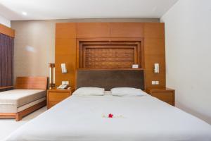 勒吉安Sinar Bali Hotel的卧室设有白色大床和木墙