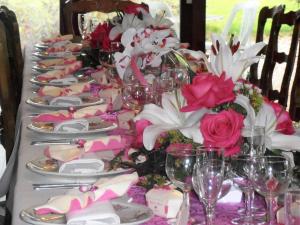La Ferté-MacéAuberge d'Andaines的长桌,带粉红色和白色的鲜花及酒杯