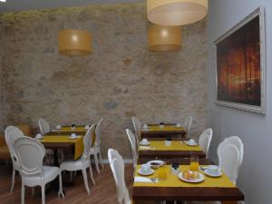 菲盖拉-达福什海滨迷人旅馆的用餐室配有木桌和白色椅子