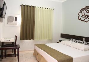 瓜伊拉Novo Hotel Herta的一间卧室配有一张床、一张桌子和一个窗户。