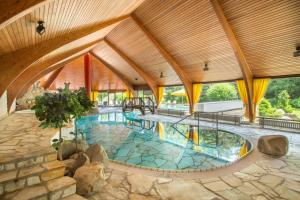 维林根斯特里克豪斯罗曼蒂克酒店的一座大型游泳池,位于一栋带木制天花板的建筑内