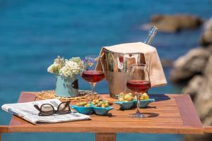 索伦托乔凡娜瑞加纳酒店的一张桌子,上面放着两杯葡萄酒和食物