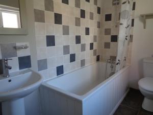 YoxfordMinsmere Cottage的带浴缸、盥洗盆和卫生间的浴室