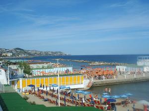 圣雷莫伊斯佩里亚酒店的海滩上摆放着椅子和遮阳伞,还有一座黄色的建筑