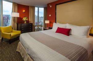 华盛顿毕考酒店及公司宿舍的酒店客房设有一张大床和一张黄色椅子