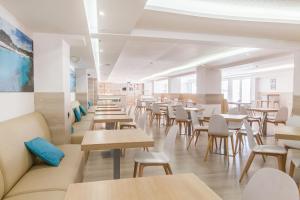 埃尔阿雷纳尔格拉西亚酒店的餐厅设有木桌、椅子和窗户。