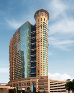 阿布扎比Grand Millennium Al Wahda Hotel and Executive Apartments Abu Dhabi的一座高大的建筑,上面有一座圆塔
