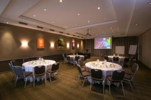 悉尼悉尼帕拉马塔美居酒店的一间会议室,配有桌椅和屏幕