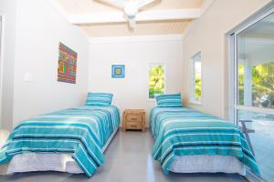 拉罗汤加Frederick and Ngamata's Beach House的配有2张床的白色墙壁和窗户客房