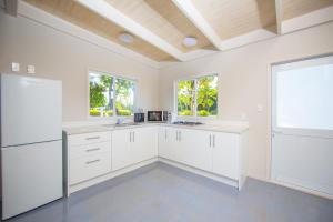 拉罗汤加Frederick and Ngamata's Beach House的白色的厨房配有白色橱柜和窗户。