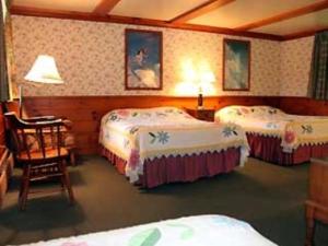 北康威白色特里斯汽车旅馆的酒店客房,设有三张床和椅子