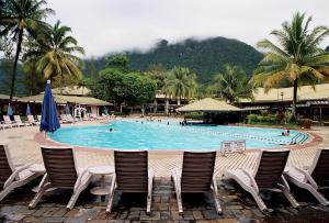 山都望达迈海滩度假村的一个带椅子的游泳池,度假村内有工作人员