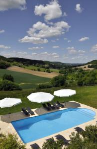 Penne-dʼAgenaisGîtes Le Relais de Roquefereau的一个带白色遮阳伞和椅子的游泳池