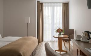 杜塞尔多夫克里斯马酒店的配有床和鲜花桌的酒店客房
