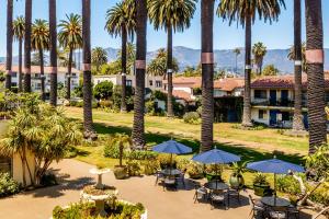 圣巴巴拉米洛圣巴巴拉酒店的棕榈树、桌子和遮阳伞的度假村