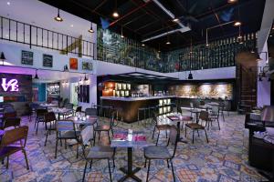 库塔favehotel Kuta Kartika Plaza的一间带桌椅的餐厅和一间酒吧