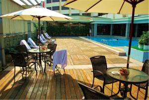中山中山国际酒店的一个带桌椅的甲板、遮阳伞和游泳池