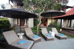 沙努尔旁多克阿玉酒店的一组椅子和遮阳伞在房子前面
