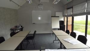 CarantillyLa Cocotte Gourmande的配有桌椅和白色屏幕的教室