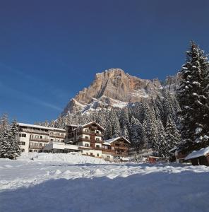 圣马蒂诺-迪卡斯特罗扎圣马蒂诺酒店的一座雪地中的建筑,背景是一座山