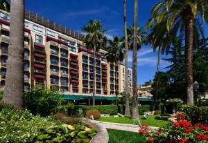 罗马帕克德普林西皮酒店的公园里种有棕榈树和鲜花的建筑