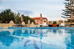 里科索翁Diwani Luxury Villas的一个带椅子的游泳池和一个背景房子