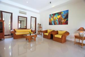 沙努尔旁多克阿玉酒店的客厅配有沙发,墙上挂有绘画作品