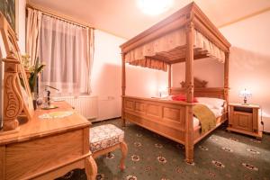 StrážaHotel Diana的一间卧室配有木制天蓬床和一张桌子
