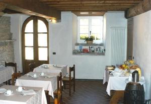 皮尼奥内拉美丽迪安娜卡萨莱酒店的一间设有白色桌椅和2个窗户的餐厅