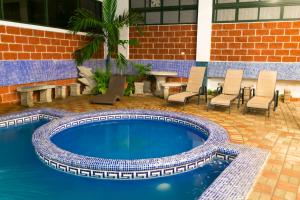 蓬塔雷纳斯蓬塔雷纳斯海滩酒店的一个带椅子和桌子的庭院内的游泳池
