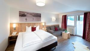 皮茨河谷圣莱昂哈德伯格兰高级酒店的卧室配有一张白色的大床和一张沙发。