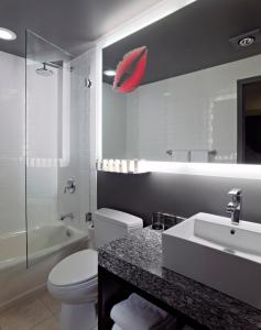 芝加哥芝加哥艾克美酒店的浴室设有白色卫生间和墙上的红色雨伞。