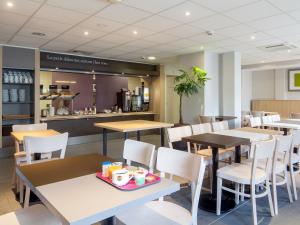 蒙彼利埃B&B HOTEL Montpellier Centre Le Millénaire的一间带桌椅和柜台的餐厅