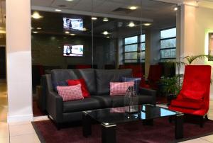 特尔福德特尔福特国际酒店的客厅配有沙发和2把红色椅子