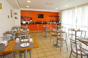 塞纳河畔伊夫里塞祖尔阿菲尔巴黎伊芙利酒店的餐厅拥有橙色的墙壁和桌椅