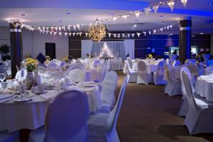 阿尔马Hotel Universel Alma的宴会厅配有白色的桌椅和吊灯