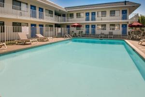 雷内克萨堪萨斯城西南列涅萨号6汽车旅馆的一座游泳池位于酒店前方,设有椅子和一座建筑