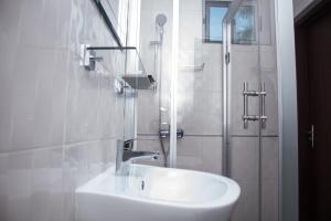 阿克拉Manjaro Suites的白色的浴室设有水槽和淋浴。