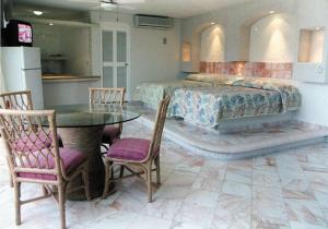 阿卡普尔科Hotel Suites Jazmín Acapulco的卧室配有一张床和一张桌子及椅子
