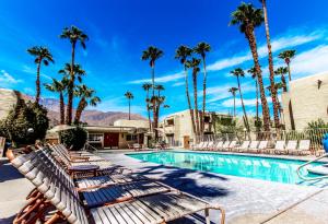 棕榈泉Desert Vacation Villas, a VRI resort的一个带躺椅的度假村游泳池,并种植了棕榈树