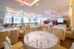 峇六拜槟城橄榄树酒店的宴会厅配有白色的桌椅