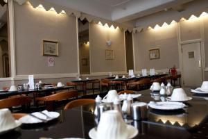 伦敦玫瑰园酒店的用餐室配有桌椅和白色餐巾