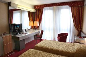 维罗纳马克西姆酒店的酒店客房设有两张床和一张书桌及电视