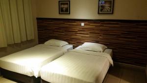 哥打京那巴鲁Hotel Iskandar的配有床头板的酒店客房内的两张床