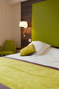 隆勒索涅Logis Hotel du Parc-Restaurant - Le Rouget de Lisle的一张带绿色床头板和绿色墙壁的床