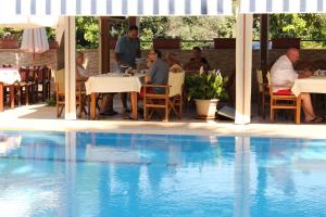 戈西克Nirvana Hotel的一群人坐在泳池旁的餐厅里