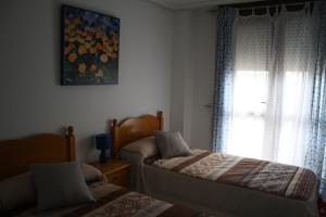 洛雷多Apartamento de Playa Somo Loredo的一间卧室设有两张床和窗户。