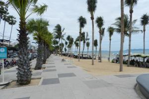 乔木提恩海滩芭堤雅尼欧新公寓的海滩上种有棕榈树的海滨步道